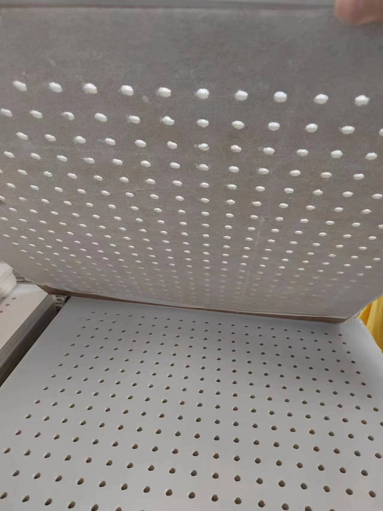 Commercial installation of perforated gypsum ceiling panels in a modern office corridor